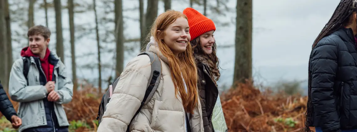 Schülern wandern lachend durch einen Wald