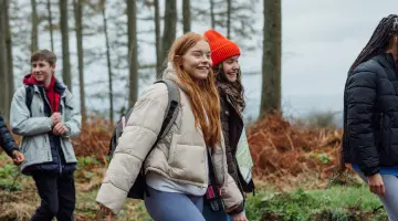Schülern wandern lachend durch einen Wald