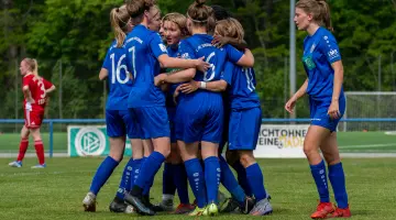 Fußballerinnen des U17 Teams des 1. FFC Turbine Potsdam im blauen Vereinstrikot umarmen sich auf dem Spielfeld.