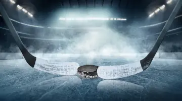 Zwei Eishockeyschläger und ein Puck liegen auf einer Eisfläche in einer großen Halle