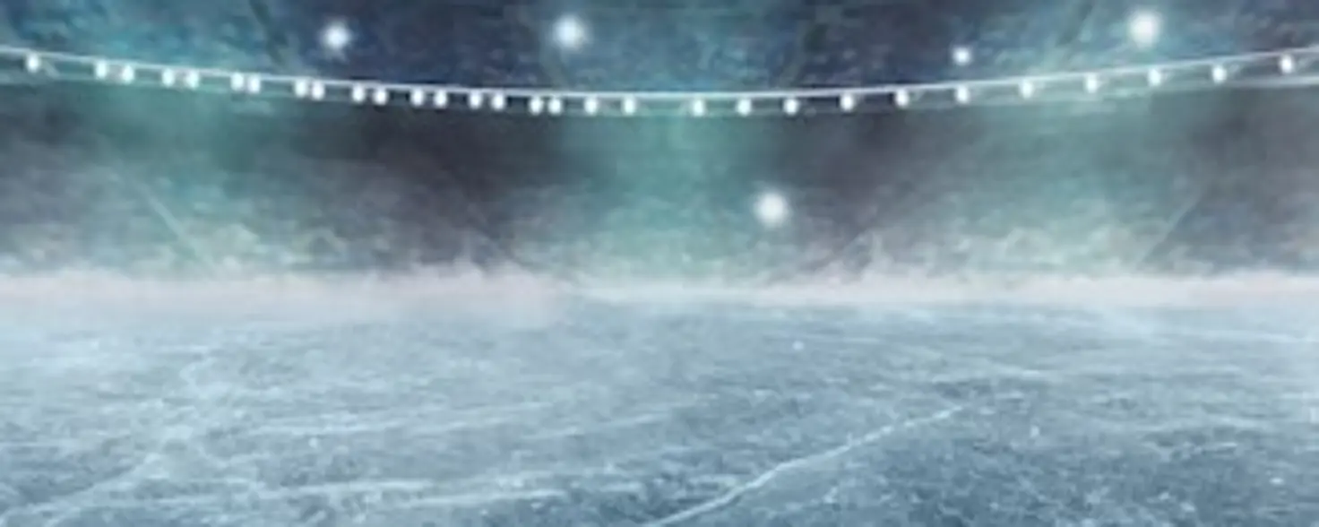 Ein Hochkant-Foto eines Eishockeyfeldes, welches mit Scheinwerfern beleuchtet wird