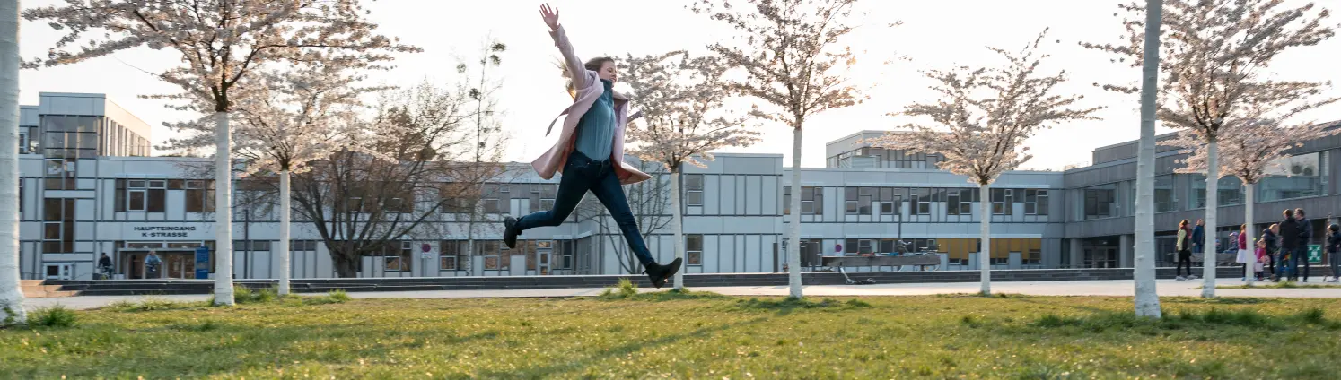 Eine Schülerin vollführt auf einer Wiese vor der Freien Universität Berlin einen Luftsprung.