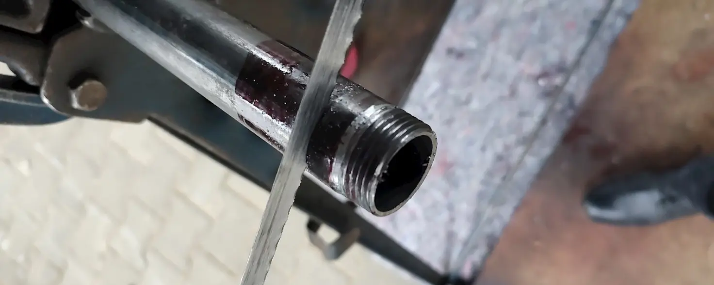 Ein Metallrohr steckt in einem Schraubstock und wird gesägt