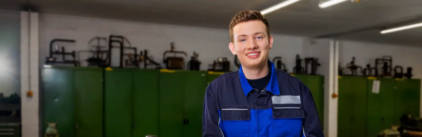 Ein Auszubildener lehnt sich an Werkbank an