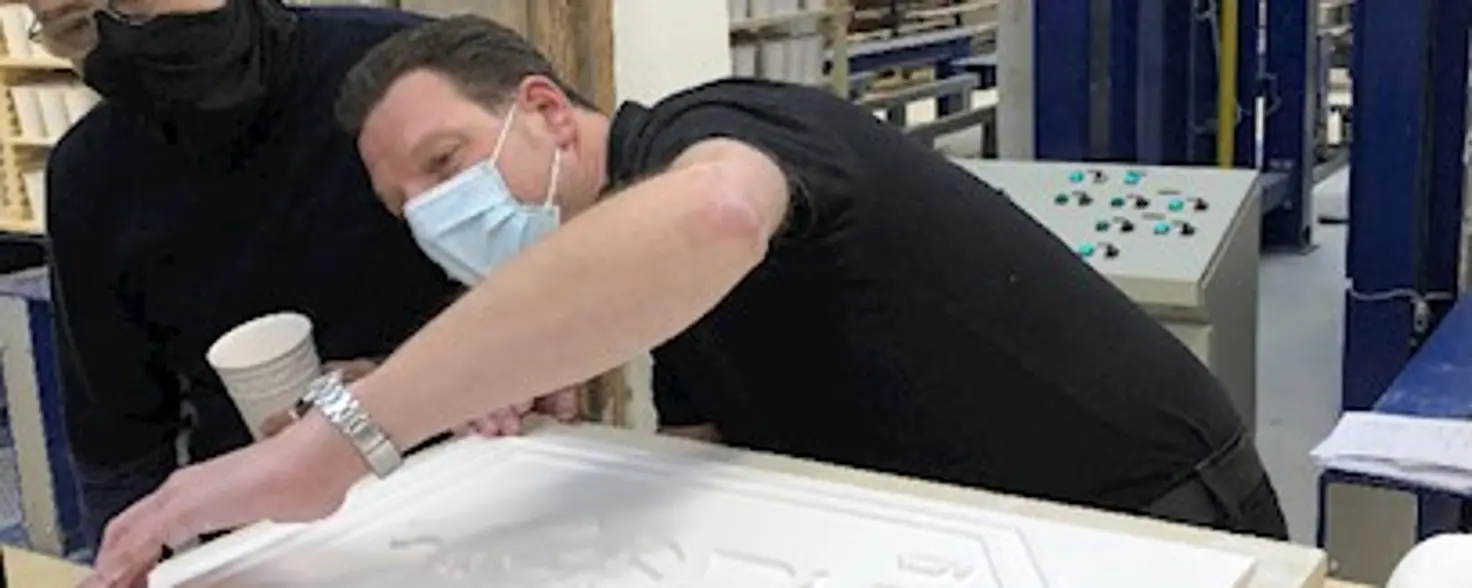 Ein Mann prüft die Qualität einer Porzellan-Tafel mit historischem GASAG-Logo
