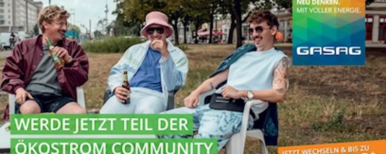Drei Männer sitzen auf weißen Plastikstühlen auf einer Grasfläche in der Stadt, zwei trinken Bier.