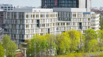 Der GASAG-Hauptsitz in Berlin-Schöneberg mit grünen Bäumen im Vordergrund.